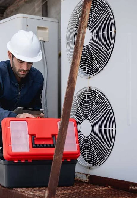 HVAC technician inspecting an outdoor air-conditioning system with service tools